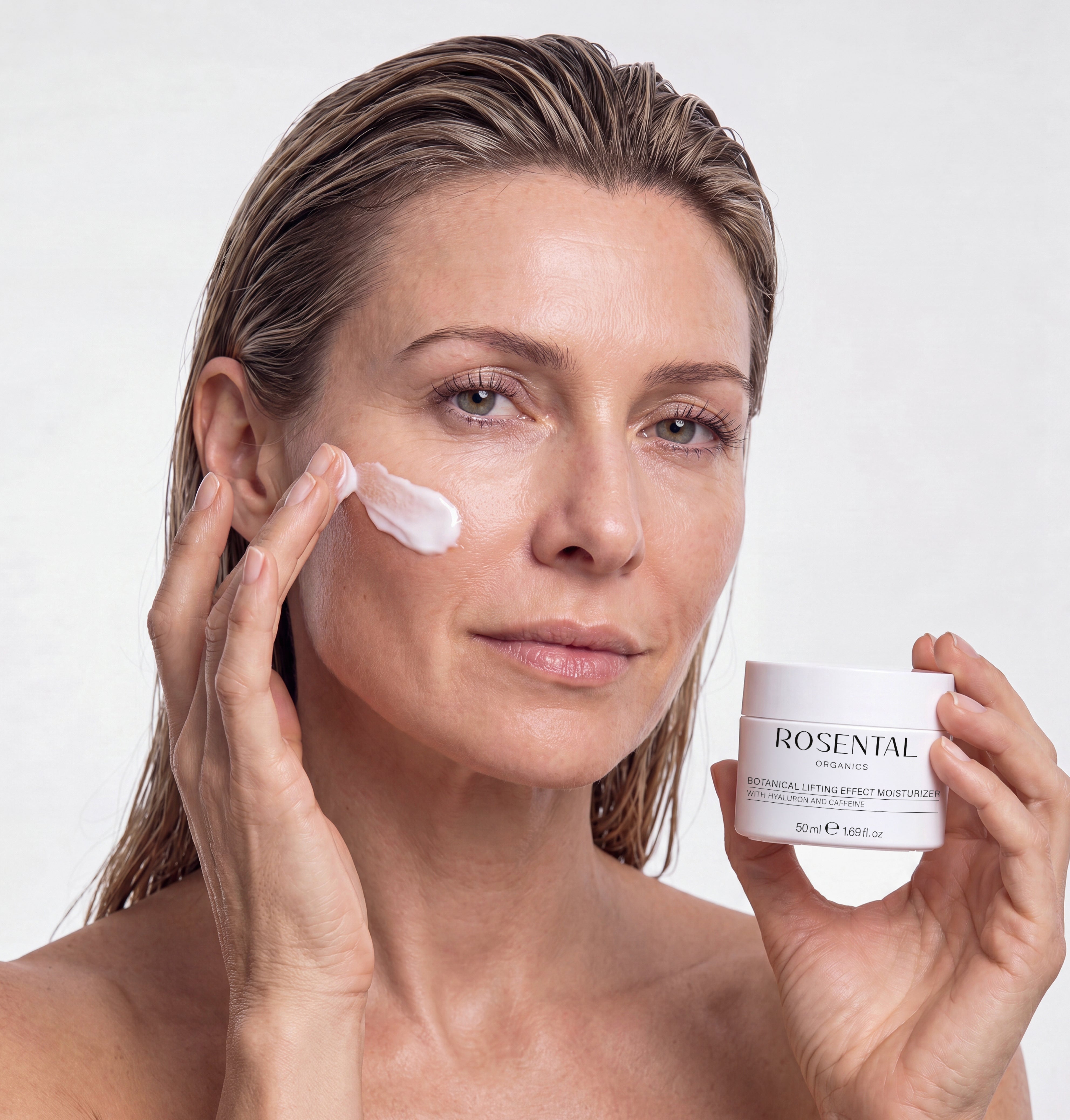 Frau trägt Botanical Lifting Effect Moisturizer von Rosental Organics auf die Wange auf und hält den Tiegel