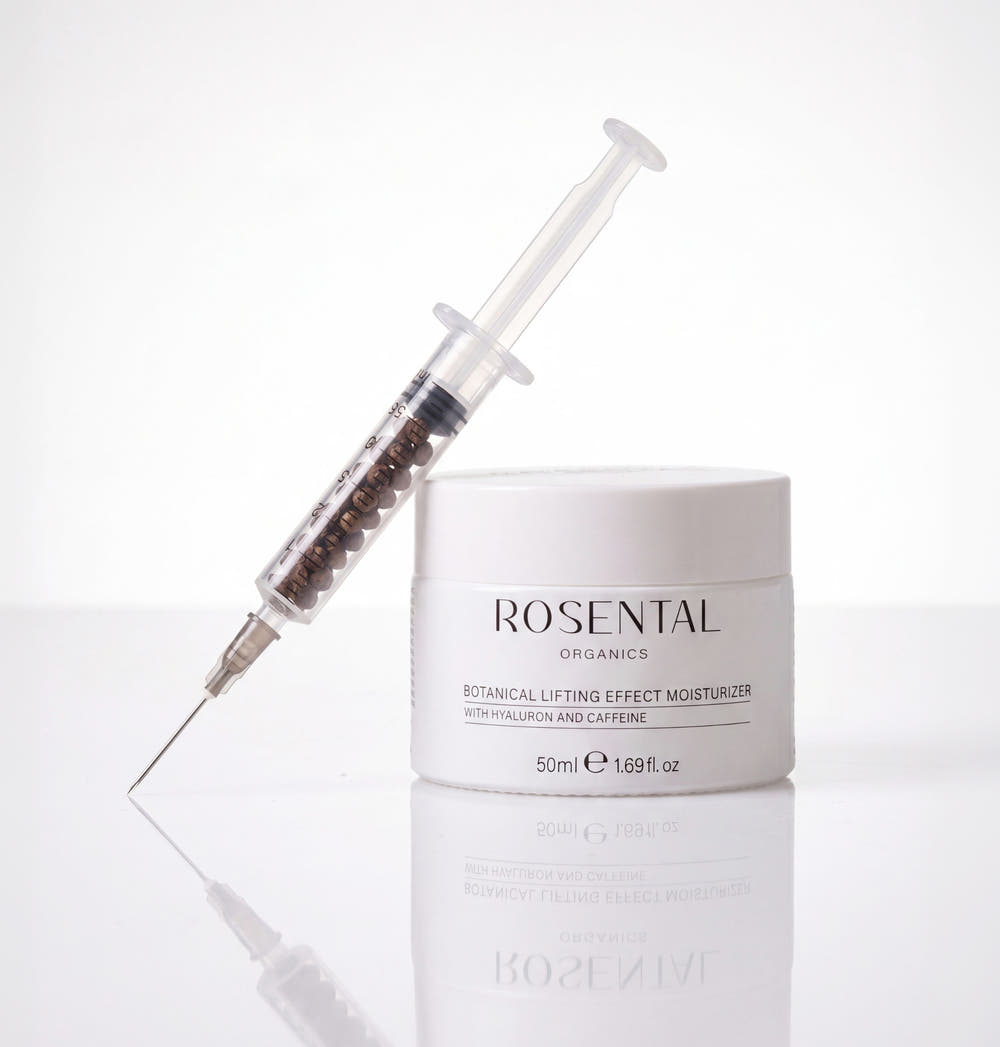 Tiegel Botanical Lifting Effect Moisturizer von Rosental Organics neben einer mit Koffein-Pellets gefüllten Spritze